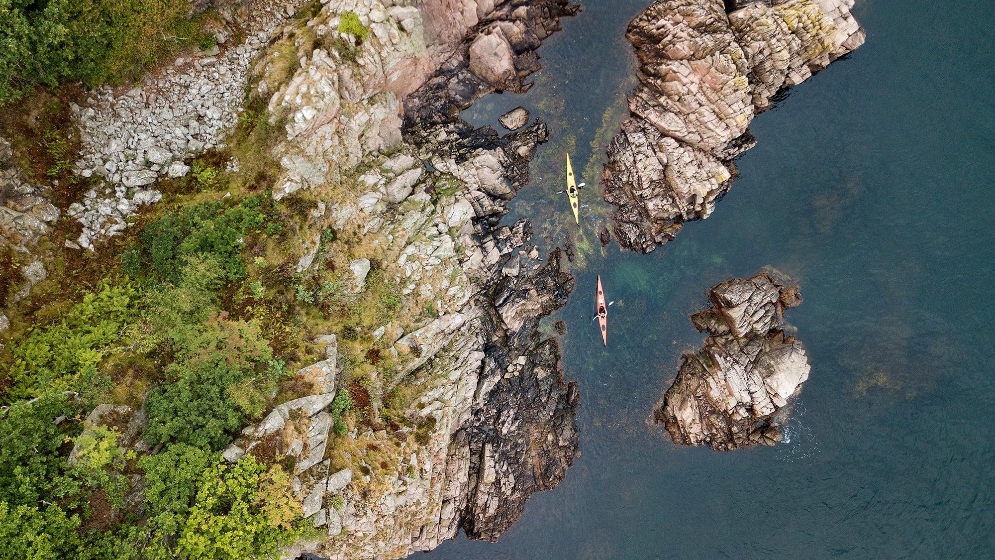 Luftfoto over klipper og en rød og gul havkajak