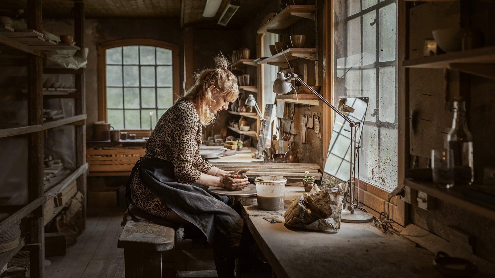 Kvinde sidder ved en drejebænk ved et vindue og arbejder